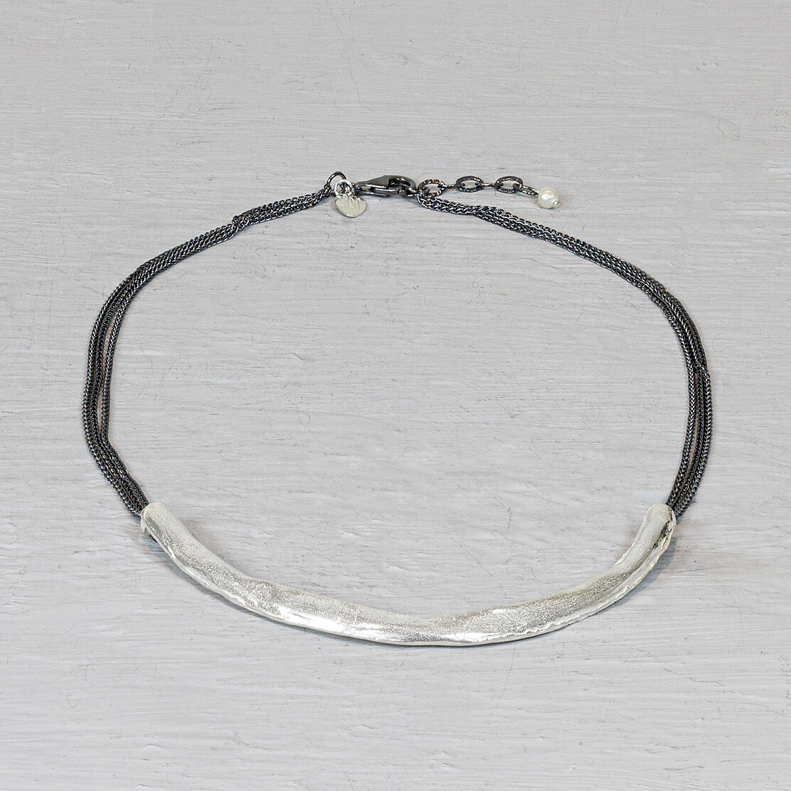 Dit collier is een combinatie van zilver en geoxideerd zilver. De drie rijen van het geoxideerde zilver staan mooi bij de lichte zilvere boog. Combineer het met een bijpassende armband om de look af te maken.