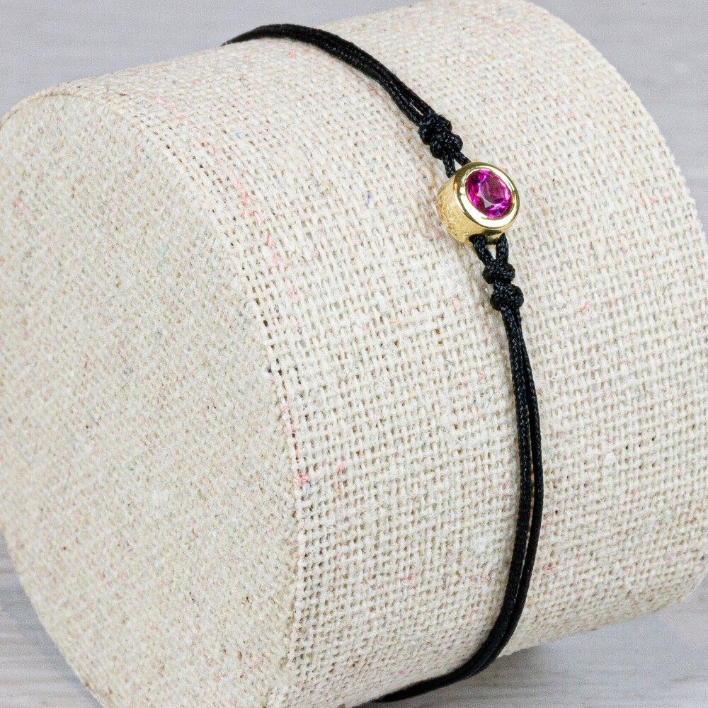 Armband koord met in het miden een knopje gemaakt van 14 karaat goud met daarin de edelsteen Roze Toermalijn. Deze armband is verstelbaar!