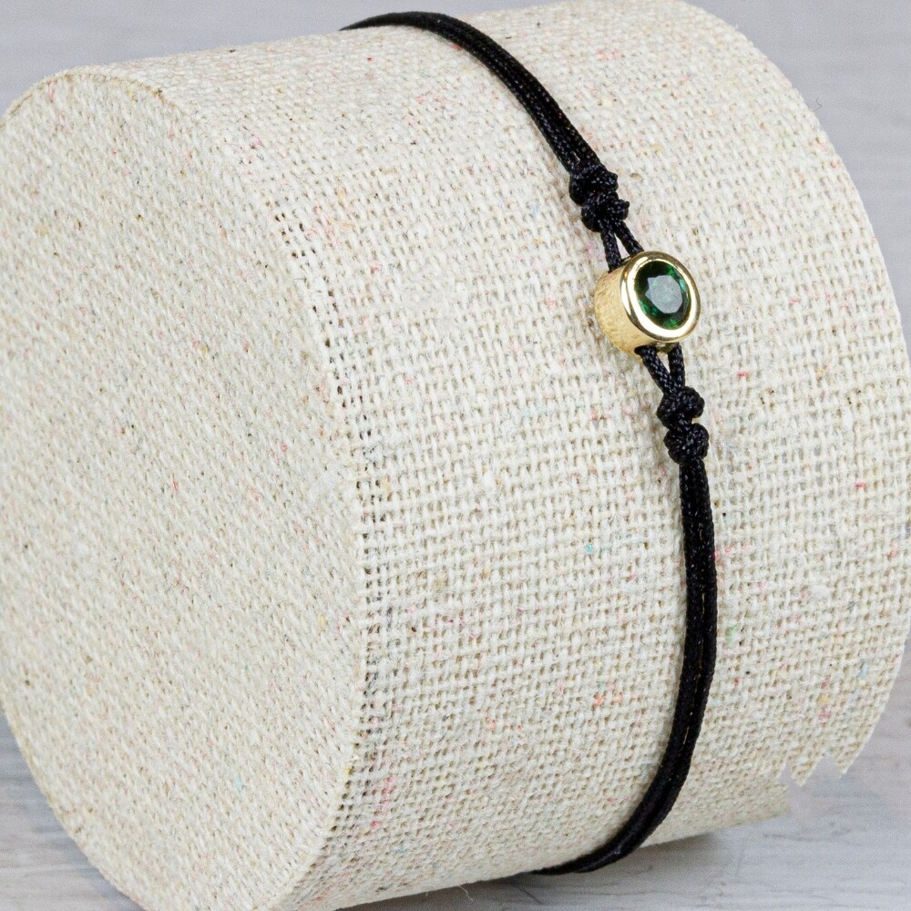 Armband koord met in het miden een knopje gemaakt van 14 karaat goud met daarin de edelsteen Groene Toermalijn. Deze armband is verstelbaar!