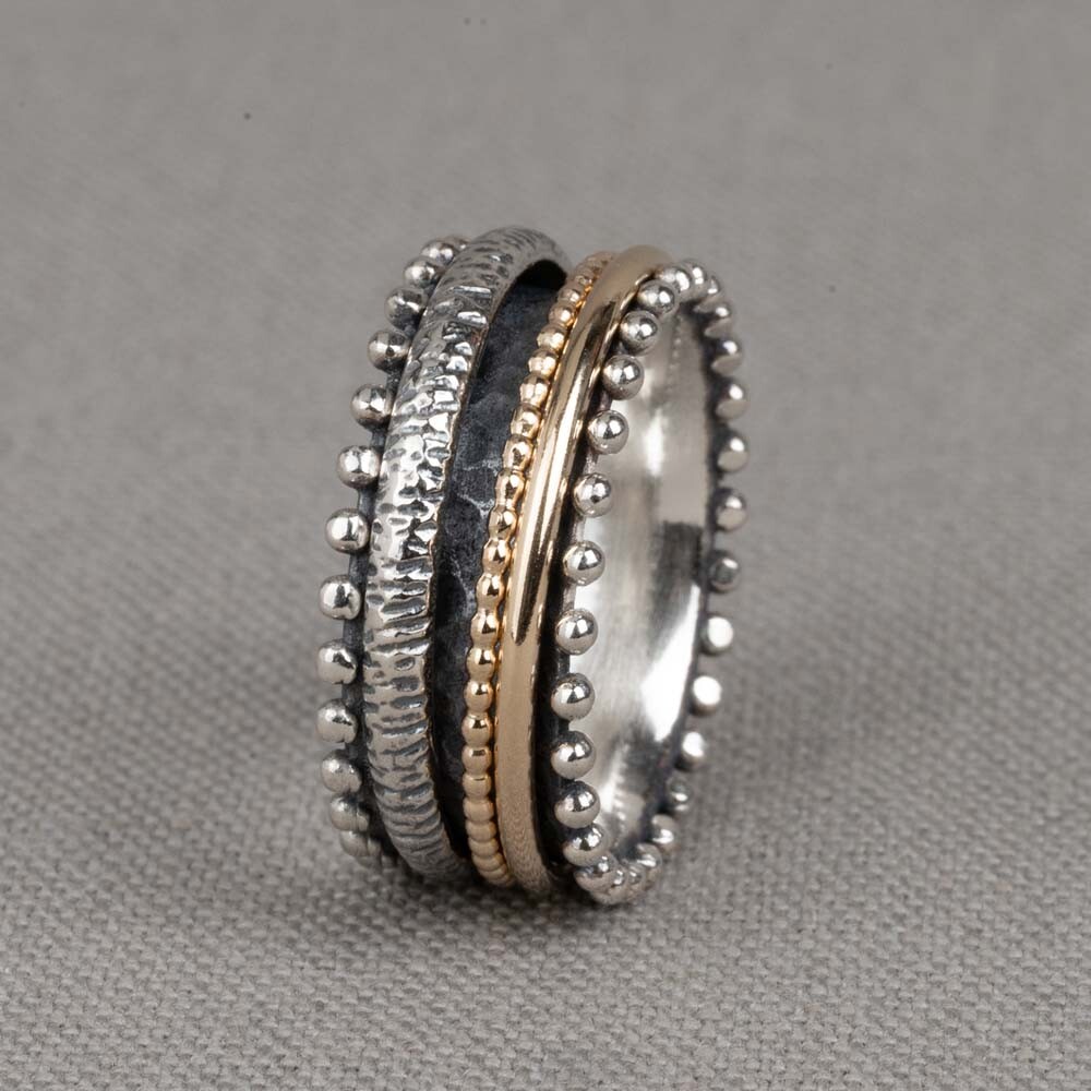 Jéh Jewels ring gemaakt van geoxideerd zilver, en goldfilled. Deze "lieve" ring heeft, net als vele van onze ringen, goldfilled bandjes die in het midden kunnen draaien. De bolletjes aan de zijkant maken deze ring extra leuk!

Materiaal: Geoxideerd zilver
Op dit sieraad is gebruik gemaakt van geoxideerd zilver, dit is een oppervlakte bewerking. Het is mogelijk dat de geoxideerde laag na verloop van tijd door slijtage gaat vervagen.

Materiaal: Goldfilled
Goldfilled komt uit Amerika en wordt daar al langer gebruikt voor de vervaardiging van sieraden met een "touch of gold" voor een betaalbare prijs. Het goldfilled blijft op kleur, is slijtvast en de goudlaag is dik genoeg om lang te kunnen genieten van de warme uitstraling van goud. Goldfilled wordt veelal ook goed verdragen door mensen die allergisch zijn voor andere metalen dan goud.

Materiaal: 925 sterling zilver
De glans van 925 sterling zilver maakt het een gewild edelmetaal voor de vervaardiging van sieraden. Het bestaat uit 92,5% puur zilver en 7,5% koper. Puur zilver is een zacht en buigzaam materiaal, het koper in 925 sterling zilver zorgt voor de stevigheid. De sieraden van Jéh Jewels zijn nikkel vrij.