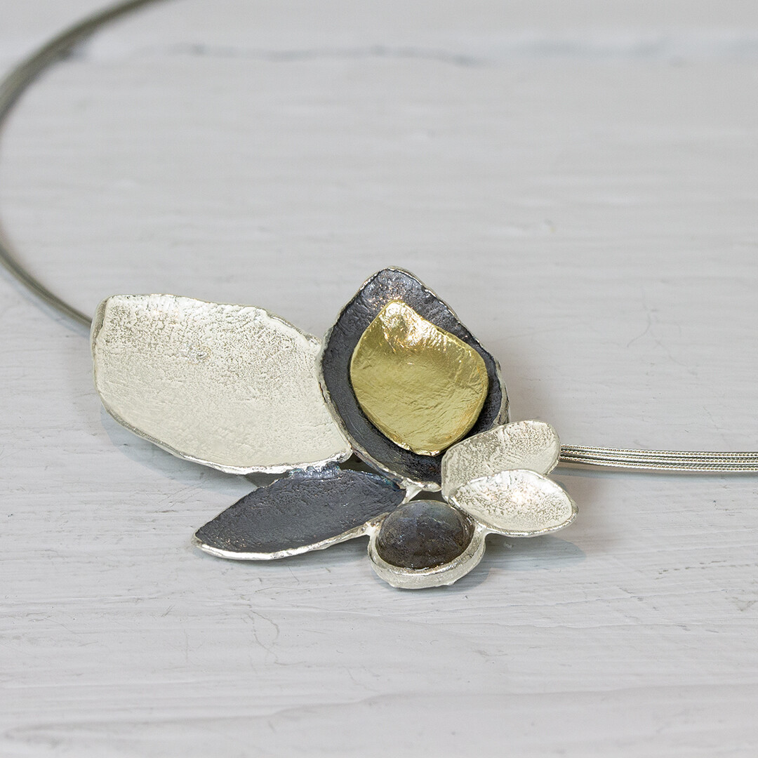 Hanger gemaakt van 925 sterling zilver, geoxideerd zilver en zilver verguld uit de collectie van Jeh Jewels. Deze bladvormige hanger, met labradoriet is prachtig aan een staaldraad spang. Labradoriet is een sterk beschermende en spirituele steen. Het beschermt het eigen energieveld (aura) tegen negatieve invloeden uit de omgeving.