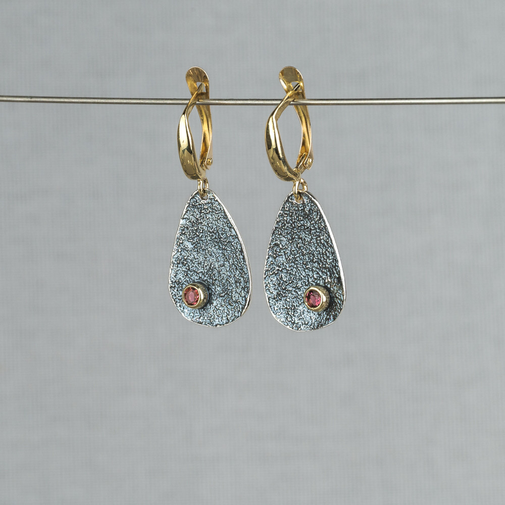 Oorhanger in de vorm van een druppel. Gemaakt van 925 (geoxideerd) sterling zilver in combinatie met 10 karaat en de edelsteen Roze Toermalijn. Toermalijn werkt aardend, beschermend en reinigend. Lees alles over deze edelsteen via onderstaande button.