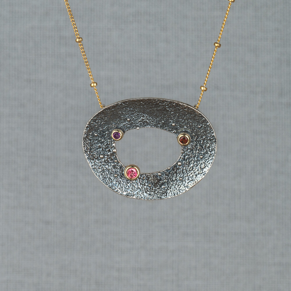 Collier gemaakt van Goldfilled met daaraan een hanger van 925 (geoxideerd) sterling zilver met daarop 10 karaat kastjes met daarin de edelstenen Roze Toermalijn, Granaat en Amethist. Lees alles over deze edelstenen via onderstaande button. Combineer dit collier met een paar oorbellen en ring uit deze lijn.