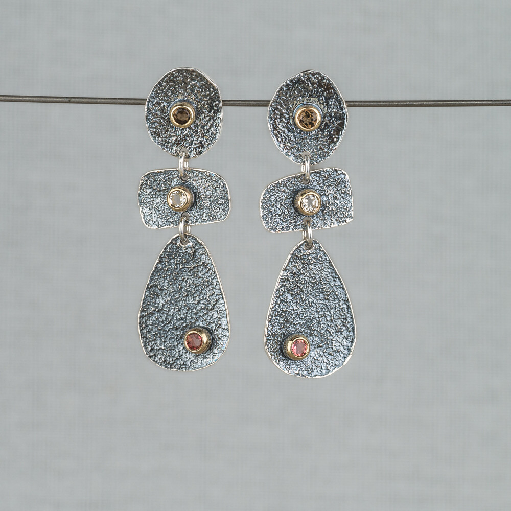 Oorsteker gemaakt van 925 (geoxideerd) sterling zilver in combinatie met 10 karaat en de edelstenen Roze Toermalijn, Rookkwarts en Witte Topaas. Lees alles over deze edelstenen via onderstaande button! Combineer met de andere sieraden uit deze lijn van Jeh Jewels.