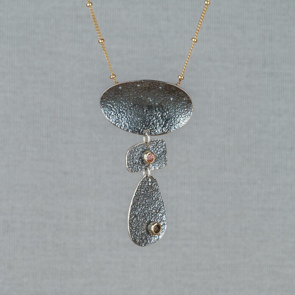 Collier gemaakt van Goldfilled met daaraan een hanger van 925 geoxideerd sterling zilver. Op de hanger vindt je de edelstenen Smokey Quarts en Roze Toermalijn in een 10 karaat kastje. Lees alles over deze stenen via onderstaande button. Combineer het collier met de bijpassende oorhangers en ring!
