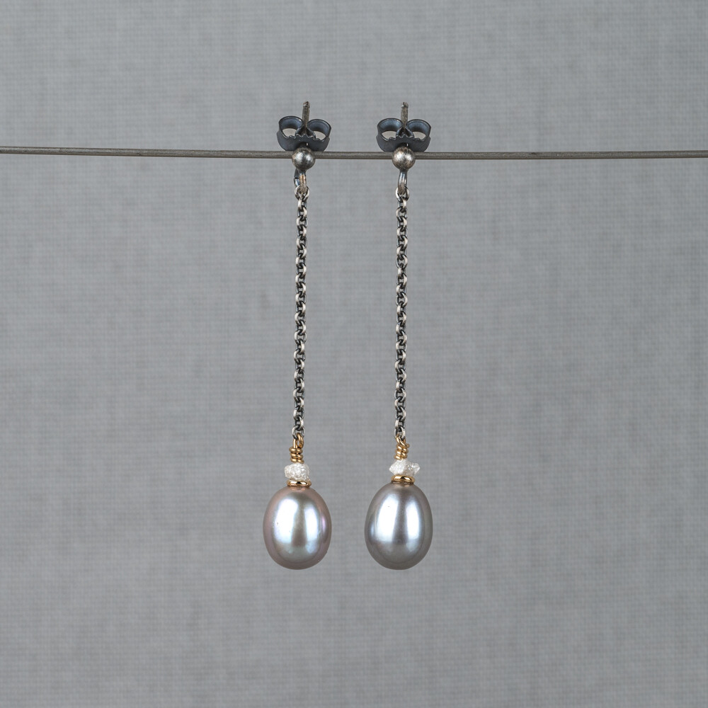 Oorbel gemaakt van 925 geoxideerd sterling zilver in combinatie met zilver verguld en de edelstenen Grijze Parel en Ruwe Diamant. Lees alles over deze edelstenen via onderstaande button. Combineer deze oorstekers met het bijpassende collier.
