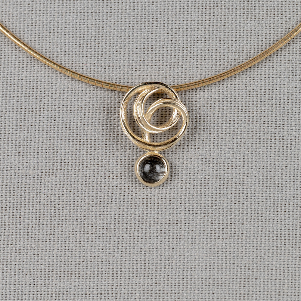 Hanger gemaakt van 14 karaat goud in combinatie met een edelsteen. Deze is verkrijgbaar met Black Rutiel, Gold Rutiel, Milky Aquamarijn, Labradoriet en Regenboog Maansteen.