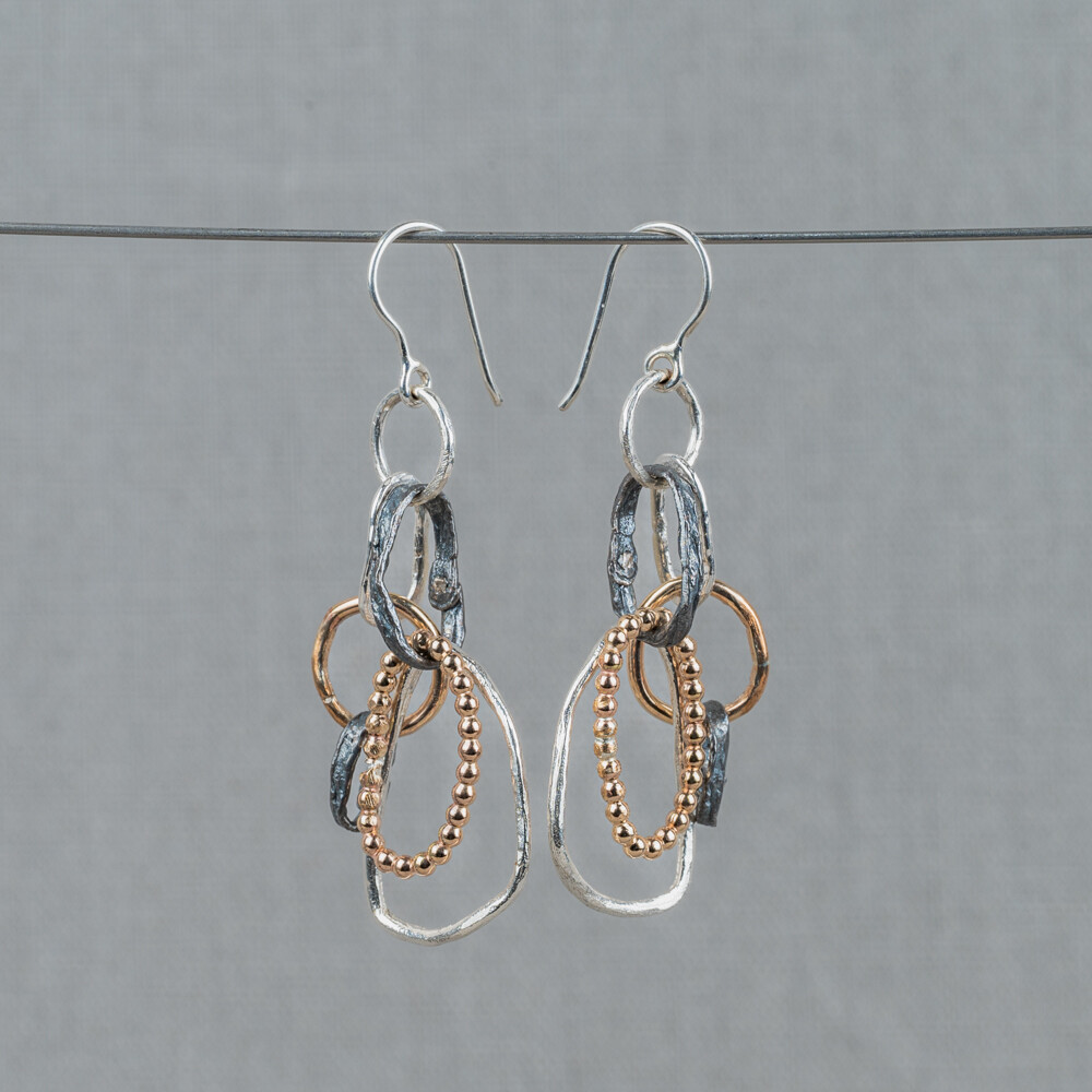 Oorhangers gemaakt van 925 sterling zilver, geoxideerd zilver en Goldfilled. Er zitten verschillende vormen ringetjes aan deze oorbellen, wat hem erg speels en uniek maakt! Combineer met een mooi collier en ring voor een complete look.