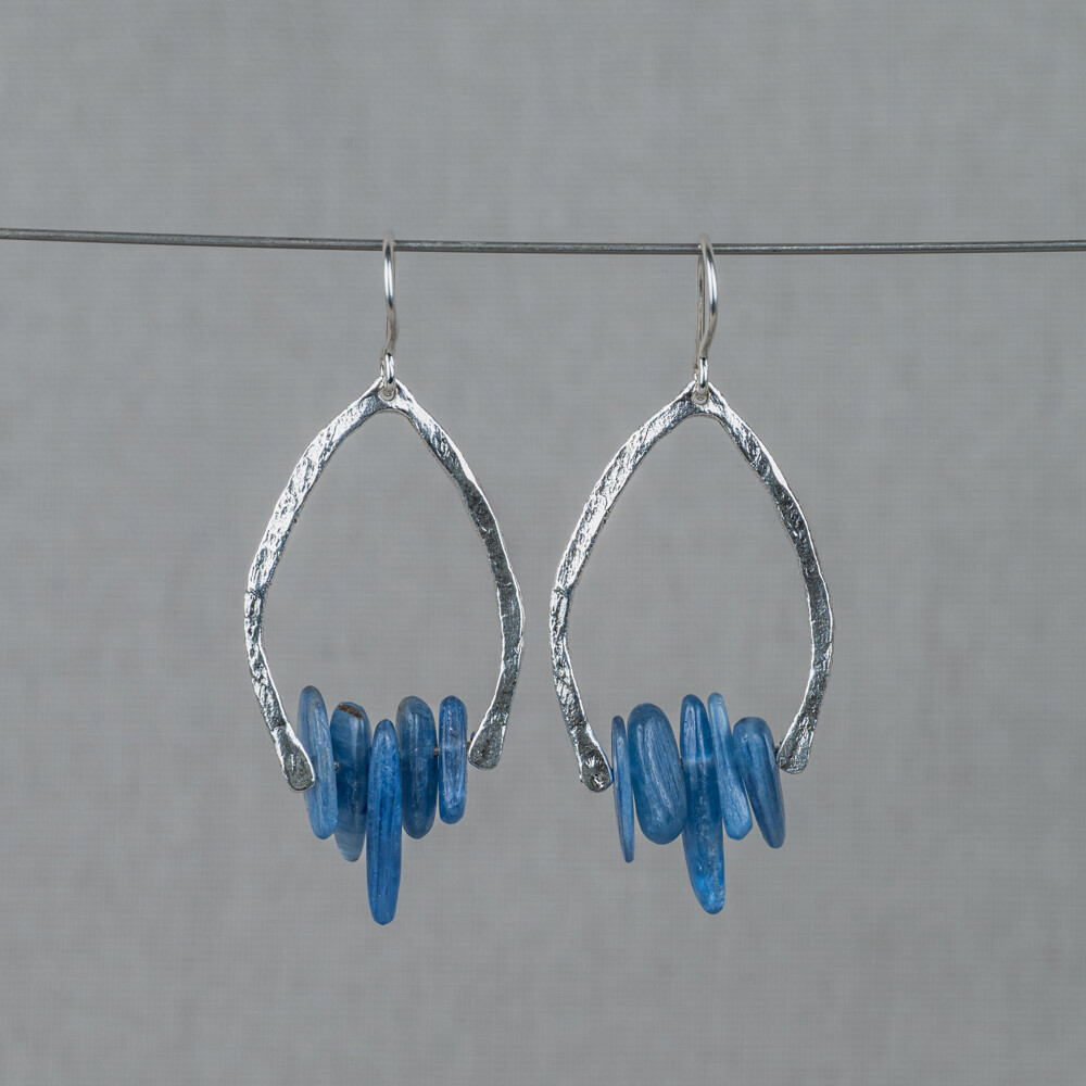 Oorbellen gemaakt van 925 sterling zilver in combinatie met de edelsteen Kyaniet. Kyaniet is een spirituele steen met een kalmerende en evenwichtige werking. De kalmerende werking zorgt voor innerlijke rust en kan zelfs helpen blokkades en angsten te doorbreken. Combineer met een mooi collier, een ring en armband voor een complete look!