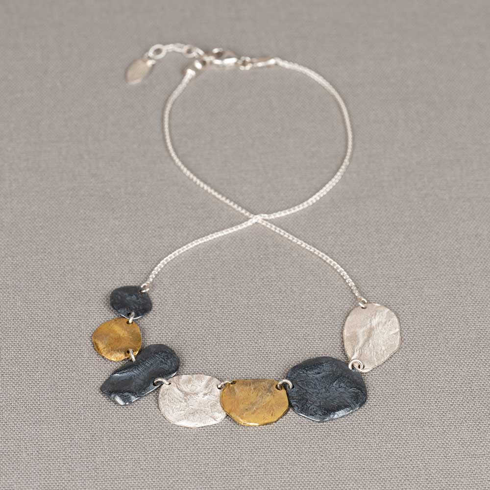 Collier gemaakt van 925 sterling zilver met daaraan schijven gemaakt van 925 sterling zilver, geoxideerd zilver en verguld. De schijven hebben een afmeting van in totaal 13 cm breed en hangen in het midden van het collier. Combineer met een mooie armband, een ring en een paar oorbellen voor een complete look!