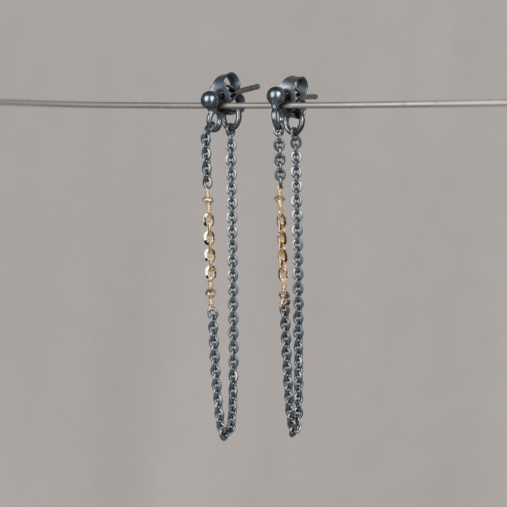 Oorbellen gemaakt van geoxideerd zilver met 14 karaat goud en 2 bruine diamanten. Combineer met het bijpassende collier en de bijpassende armband voor een complete look!