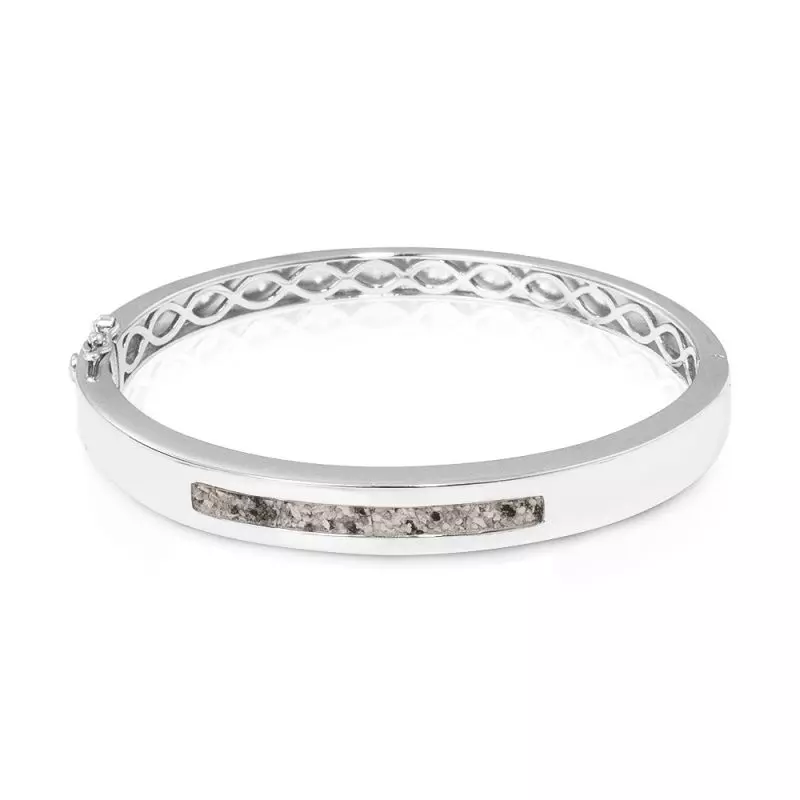Zilveren as-armband. In het midden van de as-armband bevindt zich een brede streep waarin de het as/haar/moedermelk/melktandjes verwerkt wordt.
De armband is voorzien van 2 veiligheidsslotjes.