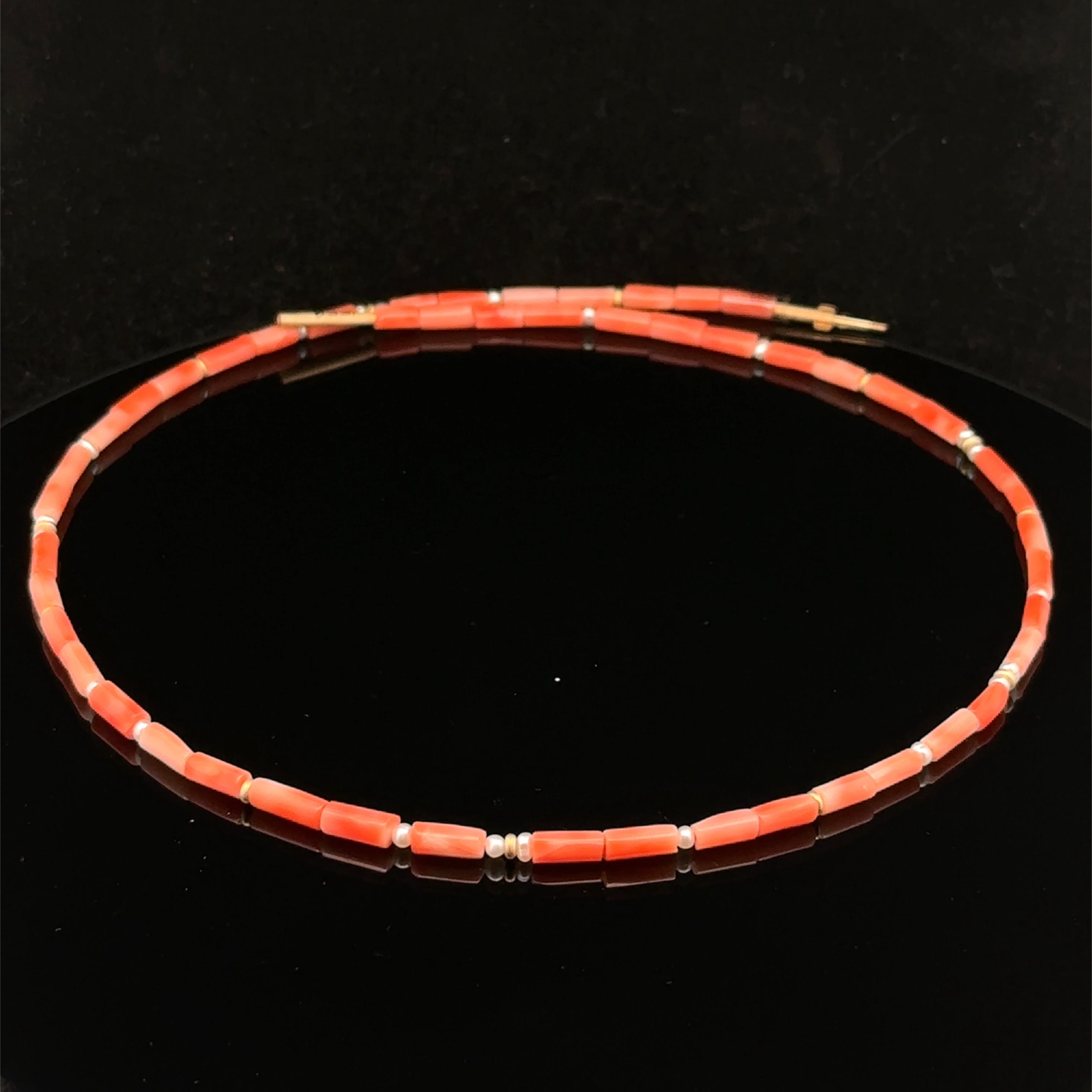 Dieses einzigartige Collier besteht aus Gelbgold 750/ooo, Koralle und Süsswasserperlchen, was ihm einen eleganten und edlen Look verleiht. Tragen Sie es alleine für einen subtilen und edlen Look oder kombinieren Sie es mit anderen Schmuckstücken für einen atemberaubenden Auftritt. Dieses Collier ist zeitlos und vielseitig, perfekt für jeden Anlass.
