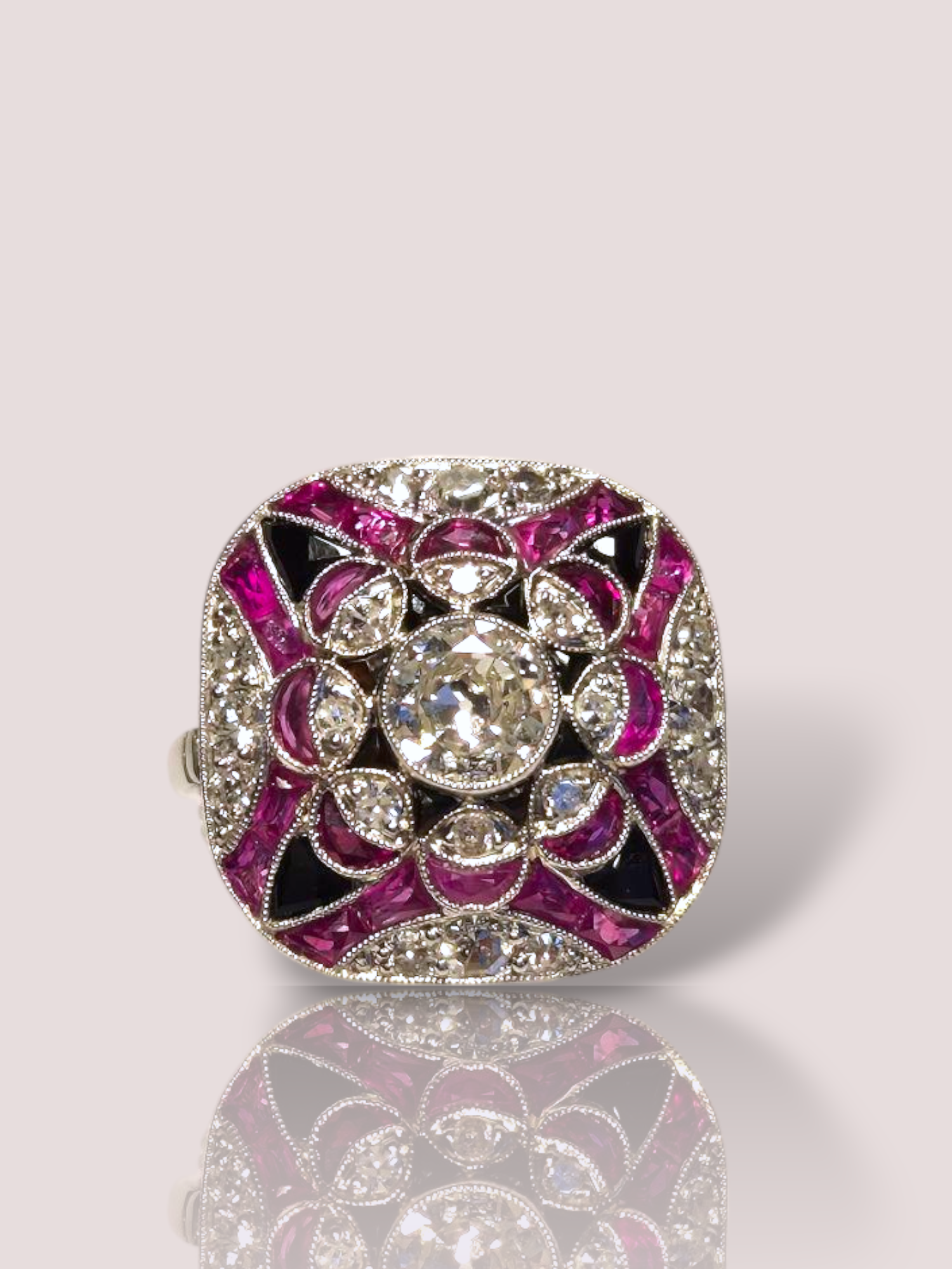 Deze vintage platina art-deco ring combineert diamanten, robijn en onyx en is een waar statement piece! De ring is vervaardigd uit platina en heeft ondanks haar omvang een slanke en sierlijke uitstraling. De ring is 3 bij 3 cm en heeft een prachtig symmetrisch ontwerp. De center stone is een Bolsjewiek geslepen diamant met een gewicht van 0,65ct, daaromheen gezet zijn nog eens 20 briljant geslepen diamanten van tezamen 0,67ct. De ring heeft daarbij nog eens 24 robijnen en 12 onyx edelstenen.

Perfect te dragen als statementstuk tijdens speciale gelegenheden, of als dagelijkse eyecatcher. Combineer met eenvoudige sieraden om de aandacht volledig op deze prachtige ring te vestigen.