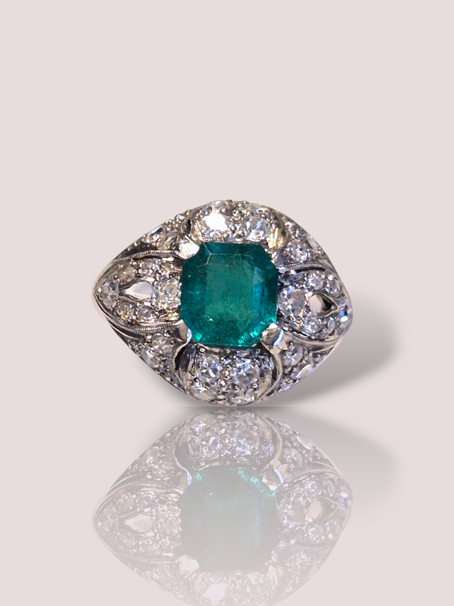 Deze vintage Art-Deco platina ring dateert uit 1920-1940 en is een prachtige toevoeging voor elke liefhebber van juwelen. Uitgevoerd met een emerald cut geslepen smaragd omringd door diverse diamanten van in totaal 1,12ct, variërend van VS1 tot P1 kwaliteit. De grotere diamanten zijn Bolsjewiek geslepen. 

Deze ring straalt absoluut tijdloze elegantie uit. Draag hem als opvallend middelpunt op een speciale gelegenheid of als uniek stuk voor dagelijks gebruik. Combineer met subtiele accessoires voor een verfijnde look.

De smaragd is 7 bij 7 mm en is zeer helder van kleur.