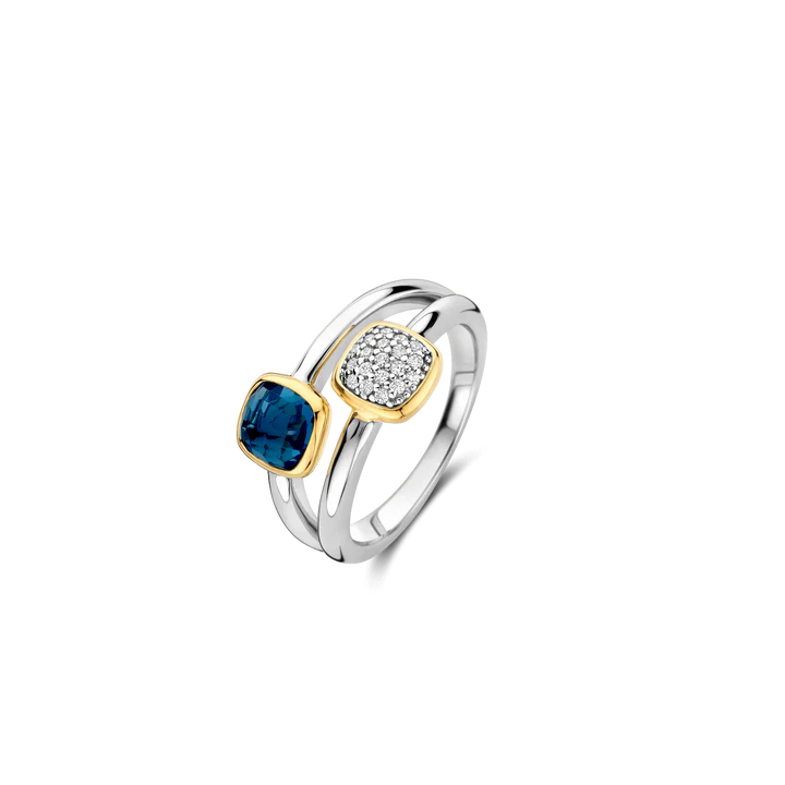 Ontdek de opvallende schoonheid van contrast met de TI SENTO ring 12352DB. Dit unieke ontwerp bestaat uit twee afzonderlijke ringen die elegant samenkomen met een ruimte ertussen. Elke ring toont een cushion-geslepen steen: de ene is versierd met een betoverende donkerblauwe steen, terwijl de andere schittert met een pavé van stralende witte cubic zirconia. Beide stenen zijn gezet in een stralend vergulde zettingen, wat hun natuurlijke schoonheid versterkt. De schachten van beide ringen zijn vervaardigd van platina-geplateerd zilver, wat zorgt voor duurzaamheid en extra glans, terwijl de open ruimte tussen de ringen een moderne en dynamische touch aan het ontwerp toevoegt. Deze ring kan zowel op zichzelf gedragen worden voor een subtiele elegantie als gecombineerd met andere TI SENTO sieraden voor een unieke, persoonlijke stijl. Hij past perfect bij elke gelegenheid, van informele uitstapjes tot formele avondbijeenkomsten. Zorgvuldig vervaardigd voor de gevoelige huid, deze nikkelvrije en hypoallergene ring zorgt voor blijvend comfort en kwaliteit.