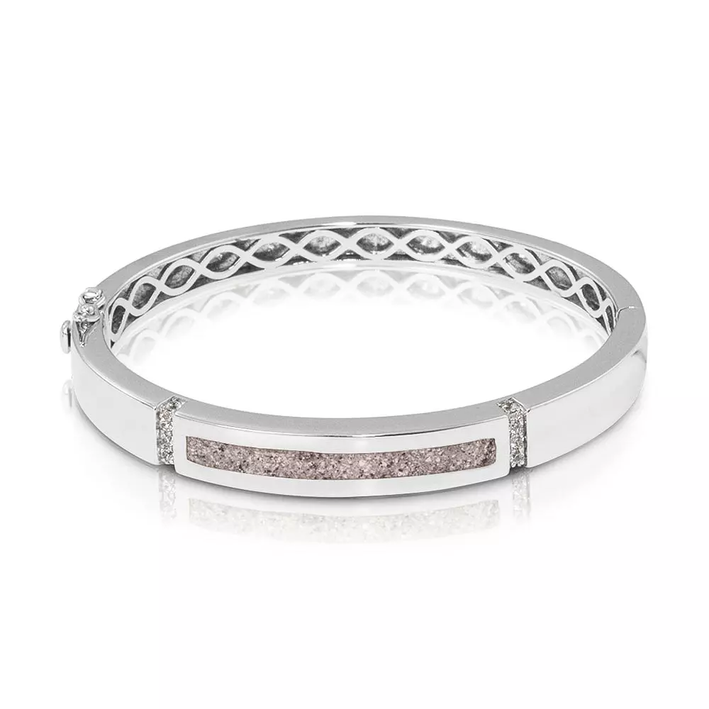 Zilveren as-armband met zirkonia. In het midden van de as-armband bevindt zich een brede streep waarin de het as/haar/moedermelk/melktandjes verwerkt wordt. De armband is voorzien van 2 extra veiligheidsslotjes.