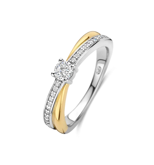 Ervaar het betoverende samenspel van licht en schaduw met deze TI SENTO goudkleurige ring 12374ZY. Dit verfijnde stuk, vervaardigd uit 925 zilver, heeft twee verstrengelde banden: één goud gekleurd, de andere schitterend met een fonkelende pavé van witte zirkonia. In het hart van dit betoverende ontwerp wordt een briljante zirkonia getoond in een delicate prongzetting, die het licht vangt en een vleugje tijdloze elegantie toevoegt. Draag deze ring solo voor een opvallend statement of combineer het met andere TI SENTO sieraden om een unieke persoonlijke stijl te creëren. 