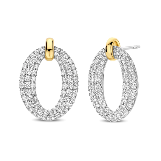 De TI SENTO vergulde pavé oorbellen 78014ZY stralen moderne glamour uit met hun gedurfde ovale silhouet, volledig bezet met glinsterende pavé gezette cubic zirconia. Deze oorbellen zijn vervaardigd van hoogwaardig 925 sterling zilver en hebben een slanke, geelgoud gekleurde schakel die elegant een sprankelende ovale vorm ophangt, wat zorgt voor een dynamisch samenspel van texturen en afwerkingen. Nikkelvrij en hypoallergeen, zorgen ze voor luxueus comfort bij elk draagmoment.