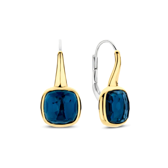 De TI SENTO oorbellen 7989DB zijn het toonbeeld van moeiteloze allure. Gemaakt van hoogwaardig 925 sterling zilver, hebben deze oorhangers een betoverende gefacetteerde diepblauwe steen, gezet in een stralend goudkleurige omlijsting die de rijke, oceaanachtige tint versterkt. Deze oorbellen bieden zowel een veilige draagervaring als sierlijke beweging, waarbij ze het licht vangen bij elke draai. De diepblauwe tint roept het mysterie van middernachtelijke wateren op, waardoor deze oorbellen een opvallende maar veelzijdige toevoeging zijn aan elke sieradencollectie. Nikkelvrij en hypoallergeen, zorgen ze voor luxueus comfort bij elk draagmoment. Of je nu strand elegantie of stedelijke chic uitstraalt, deze statement oorbellen brengen een vleugje verfijnde elegantie aan je look.