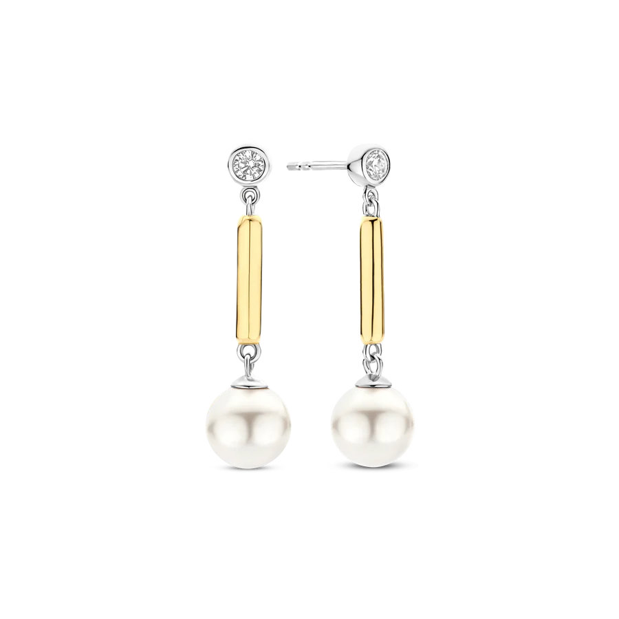 Deze TI SENTO oorbellen 78011YP combineren moderne verfijning met tijdloze glamour. Gemaakt van hoogwaardig 925 sterling zilver, hebben deze oorbellen glanzende geelgoudgekleurde accenten die prachtig contrasteren met de witte parels, voor een verfijnde en eigentijdse uitstraling. De bezel gezette cubic zirconia steker voegt een subtiele schittering toe, leidend naar een slanke vergulde staaf waar een glanzende witte parel aan hangt, die bij elke stap het licht vangt. De vloeiende beweging en strakke vorm maken deze oorbellen perfect voor zowel dagelijkse elegantie als verfijnde avondlooks. Nikkelvrij en hypoallergeen, bieden ze luxueus comfort bij elk draagmoment.