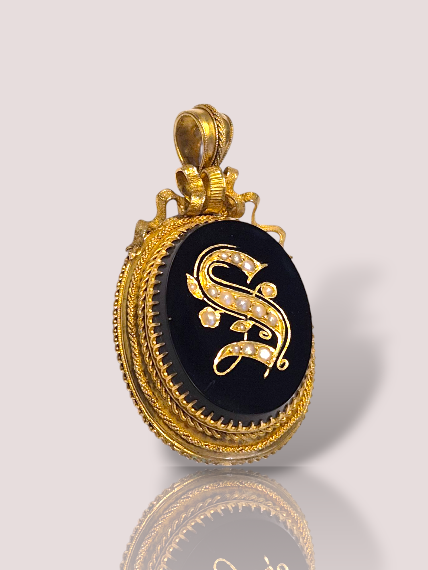 Deze Victoriaanse 14k geel gouden Onyx hanger met pareltjes straalt klassieke elegantie uit. De hanger is gemaakt van zeer fijn bewerkt goud en toont de letter S, welke bezet is met kleine pareltjes. De hanger kan aan de achterzijde geopend worden, waarbij er iets bewaard kan worden in de hanger zoals een fotootje. De hanger is ruim 7 cm lang en weegt 14,6 gram.

Perfect te combineren met een fijne gouden ketting, is deze kleursteen hanger een verfijnd sieraad voor elke gelegenheid. Draag hem dichtbij het hart voor een tijdloze uitstraling die elke outfit verrijkt. Voeg luxe en charme toe aan je juwelencollectie met dit schitterende stuk.