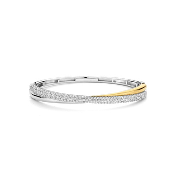 De TI SENTO armband 23071ZY is een perfecte balans tussen moderne verfijning en moeiteloze elegantie. Vervaardigd uit 925 sterling zilver en luxueus verguld, herdefinieert deze armband tijdloze schoonheid met een eigentijdse twist. Drie met elkaar verweven banden creëren een sculpturale harmonie—elk met een eigen karakter. Een slanke geelgoudgekleurde band straalt warmte en straling uit, terwijl een koele zilvergekleurde vergulde band een verfijnde, gepolijste uitstraling geeft. De laatste band schittert met pavé-set cubic zirconia, die het licht vangt bij elke beweging en het stuk voorziet van een gevoel van ingetogen glamour. Deze armband is een moeiteloze uiting van verfijnde luxe—veelzijdig genoeg voor zonnige dagen en maanverlichte avonden. Een waar symbool van eenheid en balans, het weeft schittering, elegantie en moderniteit samen in één naadloos silhouet. Nikkelvrij en hypoallergeen, biedt het comfort bij elk draagmoment. Laat dit stralende ontwerp je pols omarmen met eigentijdse charme en tijdloze verfijning.