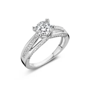 Deze ring in gerhodineerd zilver is afgewerkt met 1 grote zirconiumsteen in het midden, de band langs beide kanten is ook bezet met zirconiumstenen en bovendien zijn de zijkanten van de band eveneens bezet met zirconiumstenen
Doorsnede middelste zirconium : 6 mm