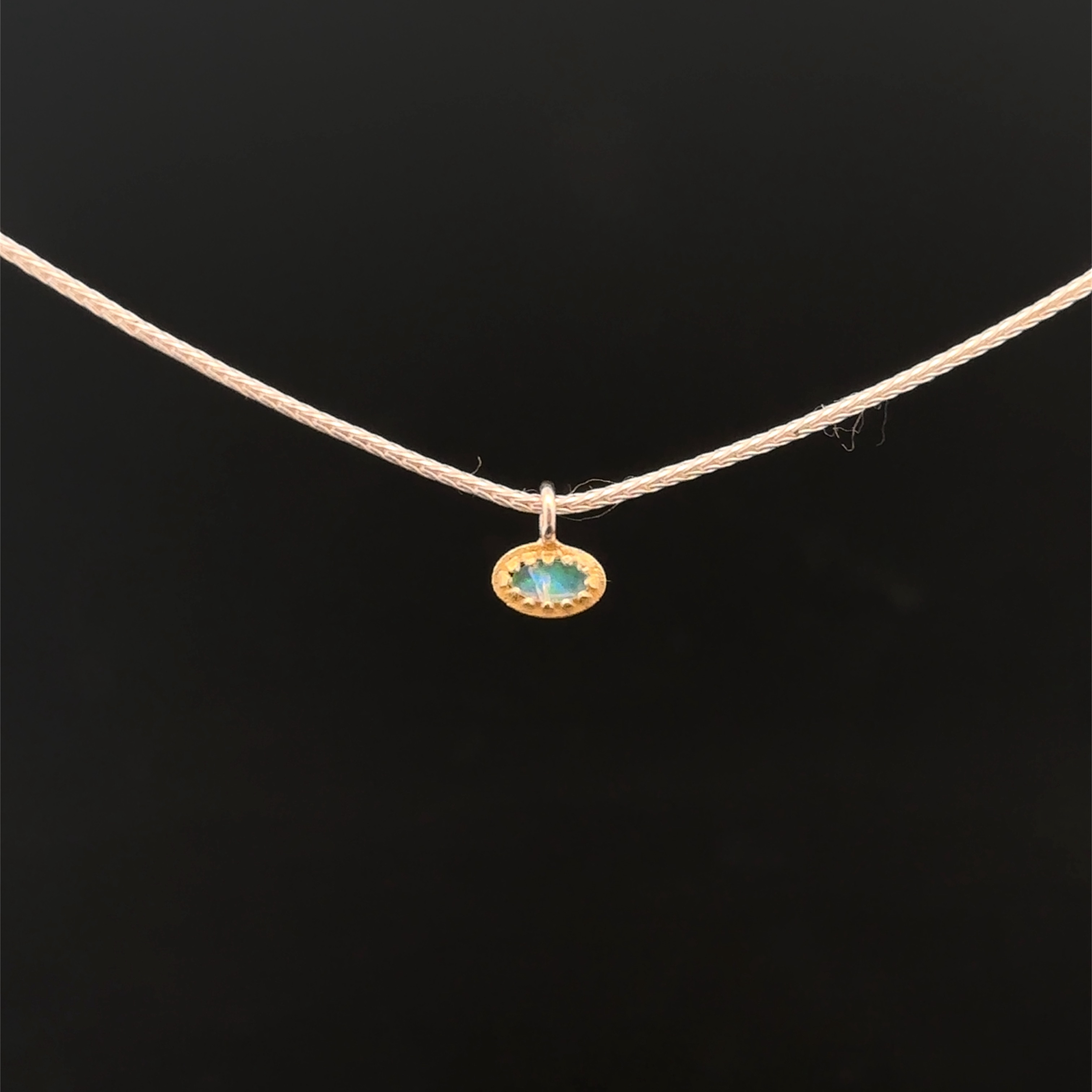 Der Anhänger besticht durch seine edle Fassung aus 18 Karat Gold (G.750) und einen echten Opal im ovalen Schliff. Er wird mit einer zarten Fuchsschwanzkette aus 925er Silber geliefert. Dieser luxuriöse Schmuck kann stilvoll mit eleganter Kleidung oder als Blickfang auf schlichten Outfits getragen werden, um Glamour zu verleihen.