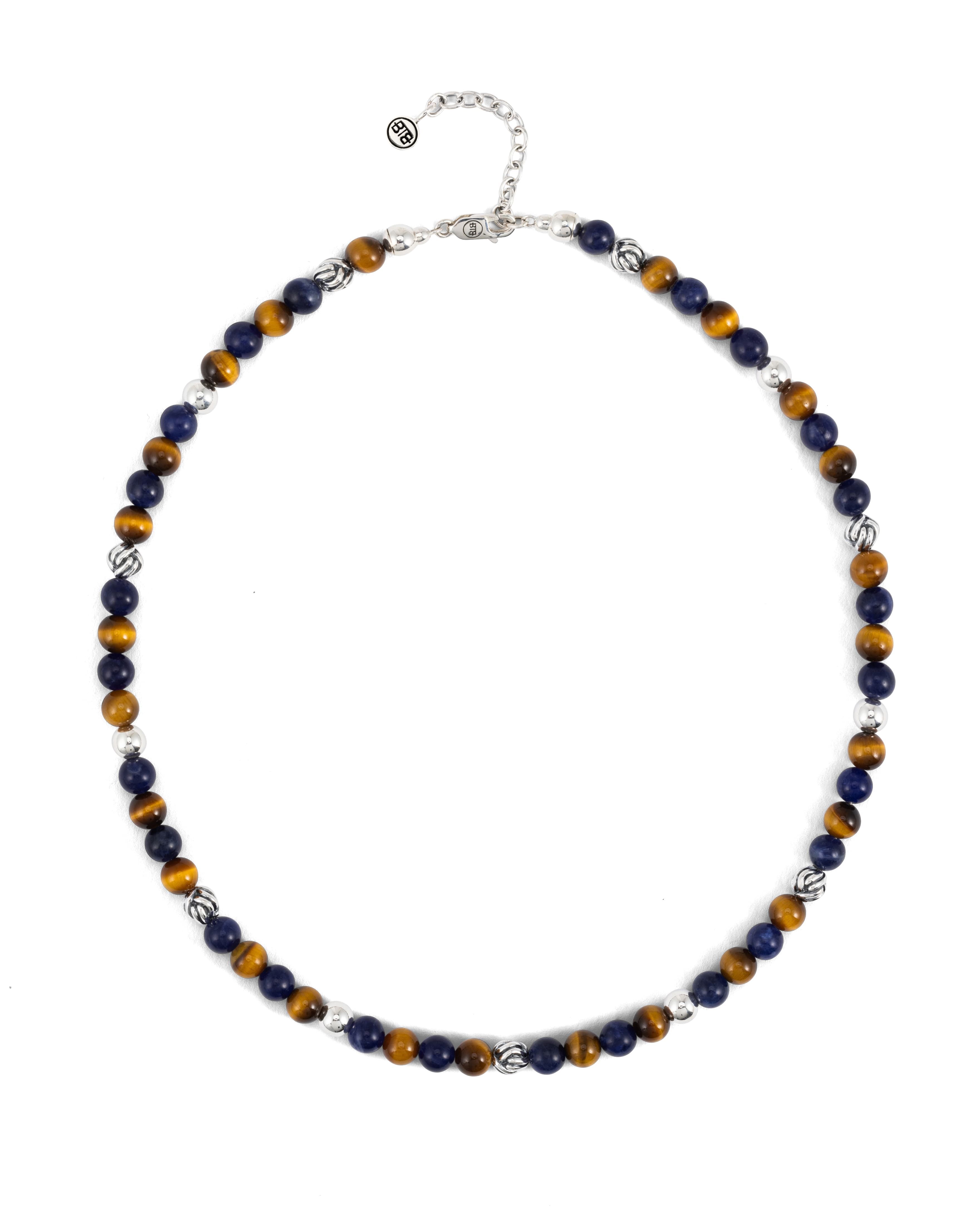 De Ketting Spirit Bead Mix Sodaliet Tijgeroog is geïnspireerd op traditionele gebedskralen en symboliseert mindfulness en in het moment leven. Deze kralenketting past perfect binnen onze Spirit Bead-collectie en bevat een mix van natuurlijke sodaliet- en tijgeroogstenen, gecombineerd met gerecycled sterling zilver, wat onze verbondenheid met de natuur en liefde voor onze planeet vertegenwoordigt. Sodaliet is een krachtige steen die communicatie en zelfexpressie bevordert, waardoor je jouw waarheid vol vertrouwen kunt spreken. In combinatie met tijgeroog, bekend om zijn goudbruine glans en het vermogen om moed, zelfvertrouwen en wilskracht te versterken, ondersteunt deze ketting persoonlijke kracht en verdrijft hij angst. Samen creëren deze stenen een harmonieuze balans van kracht en helderheid. Met zorg handgemaakt, is deze ketting een tijdloos sieraad, ontworpen in Amsterdam en met passie geproduceerd in Zuidoost-Azië. Hij is verstelbaar in maat en geschikt voor zowel mannen als vrouwen.
