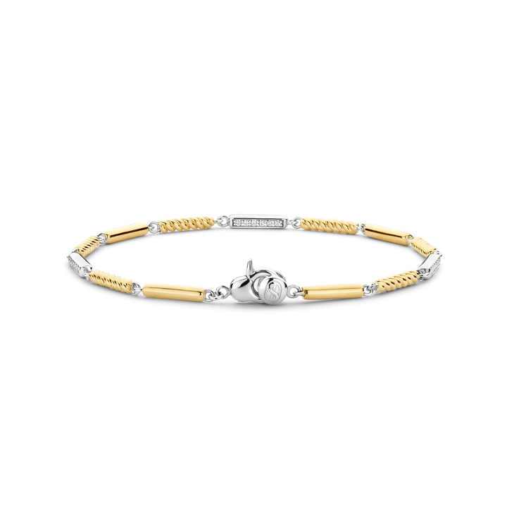 De TI SENTO armband 23069ZY verrijkt je elegantie met een stralende combinatie van luxe materialen en tijdloos design. Deze armband heeft afwisselend sterling zilveren schakels en vergulde schakels, waarvan sommige zijn verfraaid met delicate pavé-set cubic zirconia accenten, terwijl andere een speelse touwstructuur tonen. De armband is vervaardigd uit premium 925 sterling zilver en verguld. Perfect in lijn met de gloed van warme zomerdagen, voegt dit stuk verfijning en sprankeling toe aan elk ensemble. Of je nu geniet van een zonnige middag of een glamoureuze avond, de uitstekende afwerking en het harmonieuze ontwerp maken het een veelzijdig accessoire. Hypoallergeen en nikkelvrij, zorgt deze armband voor langdurig comfort en biedt blijvende kwaliteit.