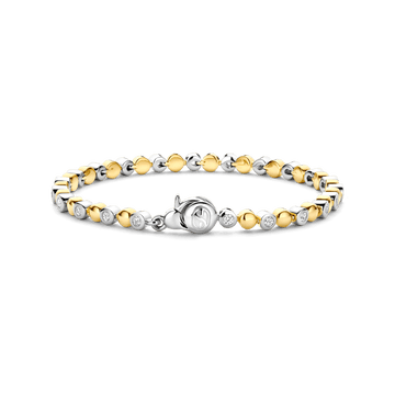 Omarm de warmte van de zomer met de TI SENTO armband 23066ZY, een moderne interpretatie van tijdloos design. Vervaardigd uit 925 sterling zilver en verguld voor bescherming en langdurige glans, biedt deze prachtige armband een betoverend spel van goudkleurige halfbubbels, afgewisseld met sprankelende witte cubic zirconia gezet in zilveren zettingen. Het centrale punt is een gestileerd TI SENTO symbool, dat een vleugje ingetogen verfijning toevoegt aan dit charmante stuk. De warme gouden tinten roepen de gloed van een zomerse zonsondergang op, wat een armband creëert dat zowel elegant als moeiteloos chic is. Zorgvuldig vervaardigd voor de gevoelige huid, zorgt deze nikkelvrije en hypoallergene armband voor langdurig comfort en kwaliteit.