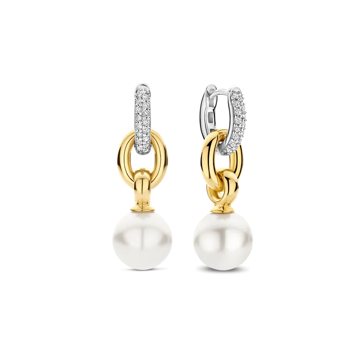 Deze TI SENTO oorbellen 78016YP zijn een gedurfde combinatie van klassieke elegantie en moderne edge. Gemaakt van hoogwaardig 925 sterling zilver, hebben deze oorbellen in elkaar grijpende goudkleurige schakels, waarvan de gladde, sculpturale vormen een opvallend statement creëren. Opgehangen aan pavégezette cubic zirconia hoepels, vangen ze het licht bij elke beweging en voegen ze precies de juiste hoeveelheid schittering toe. Een glanzende witte parel verankert het ontwerp en brengt tijdloze verfijning met een eigentijdse twist. Het samenspel van texturen en tinten maakt deze oorbellen een moeiteloze metgezel voor zowel alledaagse chic als avondglamour. Nikkelvrij en hypoallergeen, zorgen ze voor luxueus comfort bij elk draagmoment. Laat deze statement parels meebewegen met elke stap die je zet, en straal zelfvertrouwen, gratie en onmiskenbare allure uit.