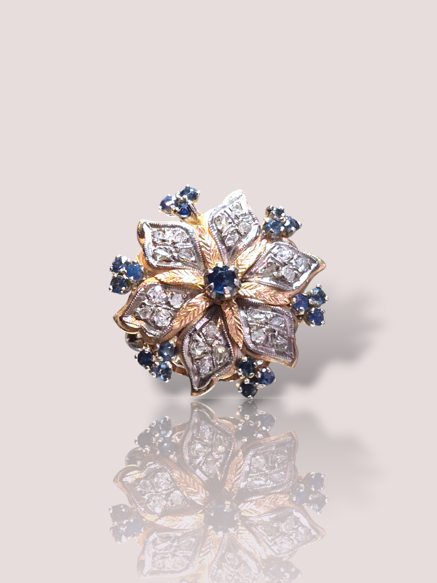 Deze prachtige vintage 14k rosegouden ring bevat schitterende saffieren en roos geslepen diamanten. De ring vormt een bloem met in het hart een bewegende saffier. De ring is op dit moment maat 21 en kan hierdoor perfect om de wijsvinger gedragen worden, de ring kan echter kan eenvoudig kleiner gemaakt worden.

Perfect als een elegant statement sieraad, ideaal voor speciale gelegenheden. Combineer met bijpassende sieraden voor een verfijnde uitstraling of draag als opvallend solitair stuk voor een vleugje vintage charme. Een tijdloze toevoeging aan elke juwelencollectie.