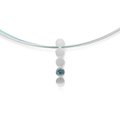 Vier ronde decoratieve elementen op een rij, bekroond door een stralend blauwe topaas (0,14 karaat), vormen deze moderne, langwerpige hanger (ontwerp Nadine Resch). Perfect te combineren met de bijpassende oorbellen en ring. Een sensuele, gebogen vorm en een consequent karakteristiek designhandschrift kenmerken de sieradencreaties van de in Düsseldorf gevestigde freelance ontwerpster Nadine Resch. Haar veelzijdige ontwerpen zorgen steeds voor nieuwe impulsen en verzetten zich tegen de uniformiteit van vandaag. “Ik wil dat elk sieraad dat ik maak de potentie heeft om een ​​favoriet te worden.” (Nadine Resch). De hanger is excl. collier