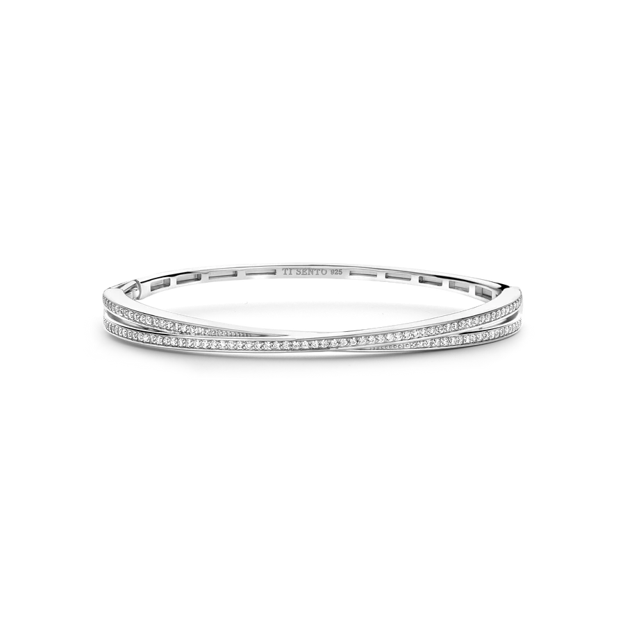 De TI SENTO armband 23072ZI is een tijdloze klassieker, vervaardigd uit premium 925 sterling zilver en verguld voor een elegante en duurzame glans. Dit adembenemende ontwerp heeft een verweven structuur: één slanke en gepolijste zilvergekleurde bangle en de andere gedecoreerd met een schitterende pavé van cubic zirconia, wat zorgt voor een harmonieuze balans tussen sprankeling en verfijning. Perfect voor de zomer, vangt deze bangle de essentie van moeiteloze elegantie, die de heldere, zonovergoten dagen en koele, serene avonden weerspiegelt. Het strakke en klassieke silhouet maakt het een ideaal accessoire voor zowel casual uitjes als bijzondere gelegenheden. Hypoallergeen en nikkelvrij, biedt deze armband ultiem comfort en kwaliteit, waardoor het een veelzijdig en gekoesterd stuk is om je sieradencollectie compleet te maken.

Deze bangle is in 3 maten verkrijgbaar.