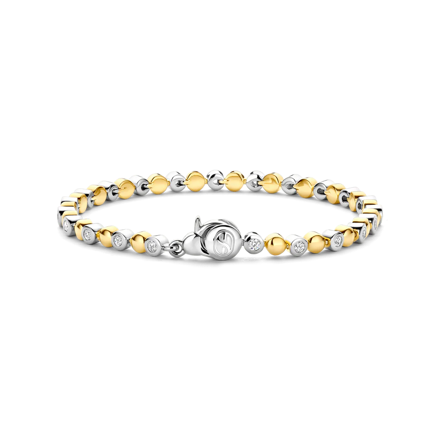 Omarm de warmte van de zomer met de TI SENTO armband 23066ZY, een moderne interpretatie van tijdloos design. Vervaardigd uit 925 sterling zilver en verguld voor bescherming en langdurige glans, biedt deze prachtige armband een betoverend spel van goudkleurige halfbubbels, afgewisseld met sprankelende witte cubic zirconia gezet in zilveren zettingen. Het centrale punt is een gestileerd TI SENTO symbool, dat een vleugje ingetogen verfijning toevoegt aan dit charmante stuk. De warme gouden tinten roepen de gloed van een zomerse zonsondergang op, wat een armband creëert dat zowel elegant als moeiteloos chic is. Zorgvuldig vervaardigd voor de gevoelige huid, zorgt deze nikkelvrije en hypoallergene armband voor langdurig comfort en kwaliteit.