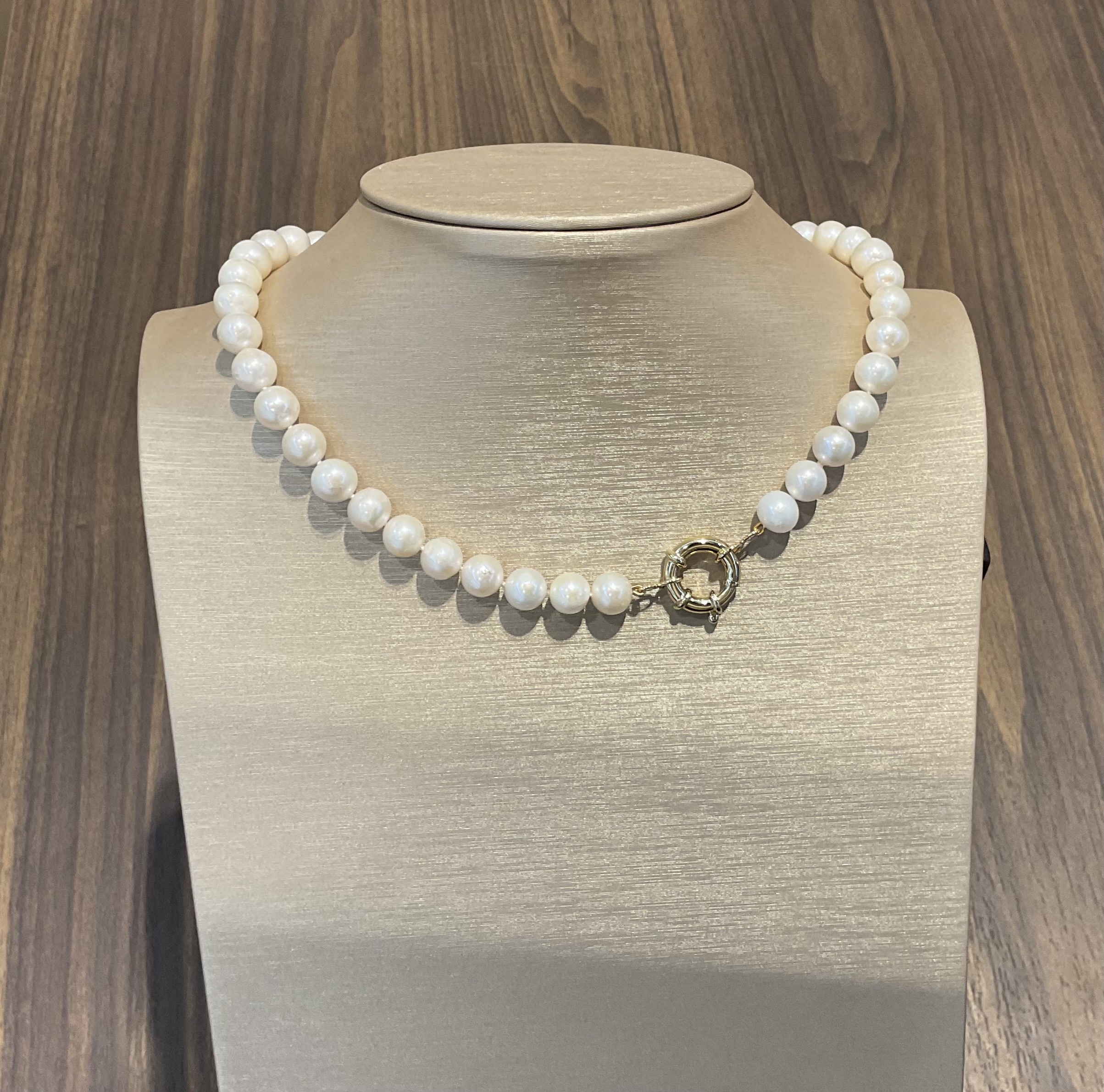 De Parel collier met gouden veerring, zoetwaterparel rond 10mm, is een verfijnde ketting met een parel van 10mm en een elegante gouden veerring, 45 cm lang. Perfect voor zowel formele als informele gelegenheden. Draag hem met een elegante blouse of avondjurk voor een verfijnde uitstraling. Categorie: Sieraad; Type: Ketting.