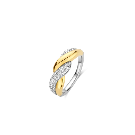 Laat je vinger omhuld worden door de liefdevolle omarming van deze TI SENTO goudkleurige ring 12370ZY, een gedurfd ontwerp dat verbinding en contrast viert. Vervaardigd uit hoogwaardig 925 zilver, heeft dit opvallende stuk twee verstrengelde banden: één stralend verguld, wat warmte en weelde uitstraalt, en de andere versierd met een pavé van fonkelende witte zirkonia stenen voor een vleugje schitterende pracht. Het samenspel van de gouden kleur, het zilver en de pavé schittering creëert een harmonieuze balans van gedurfde elegantie en gratie, waardoor het het perfecte statement stuk is voor elke gelegenheid. Zorgvuldig vervaardigd voor de gevoelige huid, deze nikkelvrije en hypoallergene ring garandeert langdurig comfort en kwaliteit.