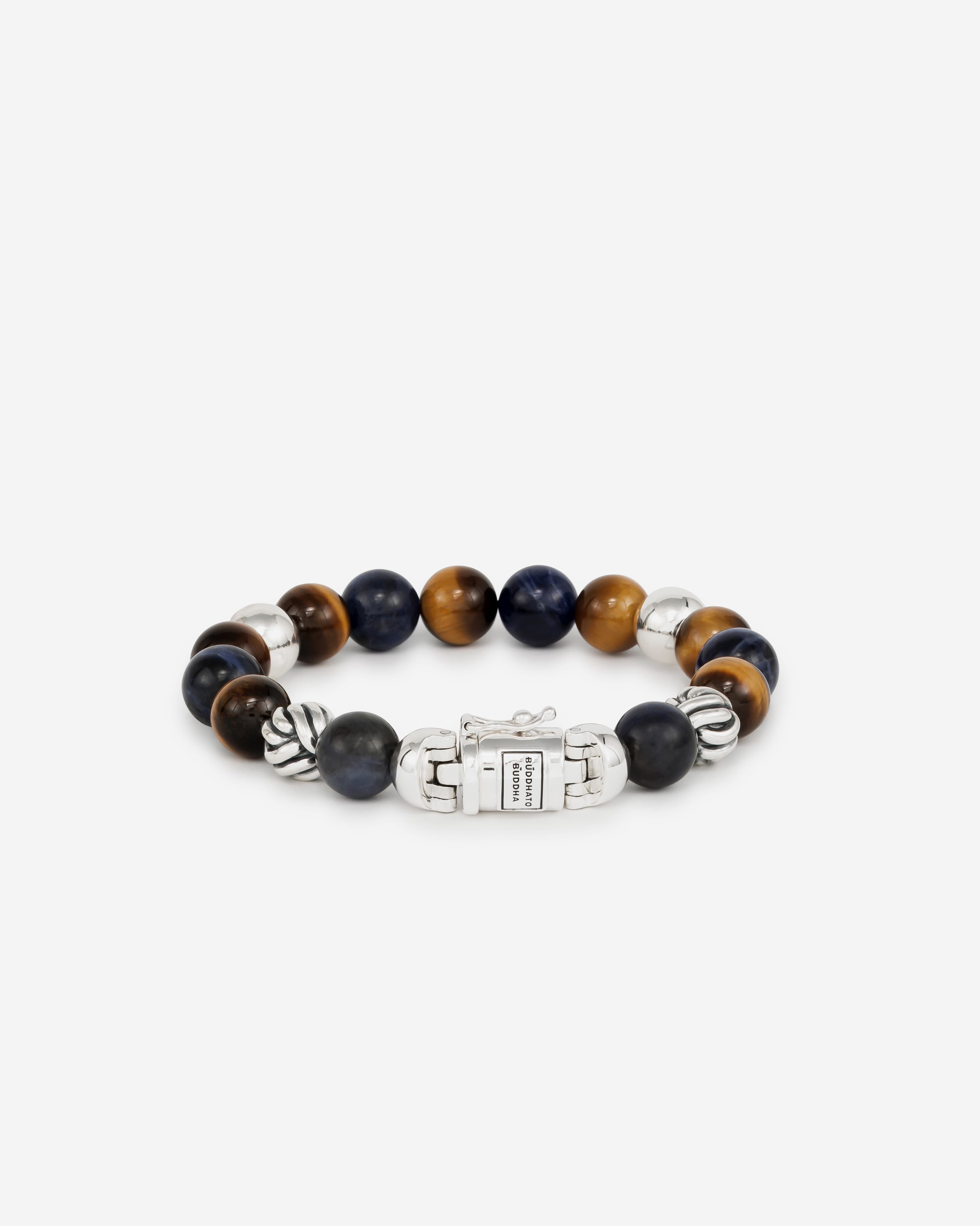 De Spirit Bead Sodalite Tiger oogarmband is gebaseerd op bidkralen en is vertaald naar een Buddha to Buddha ontwerp met zijn iconische sterling zilveren slot. We omarmen de edelsteenkralen vanwege hun schoonheid en spirituele betekenis. Deze armband heeft sodalietstenen afgewisseld met tijgeroogstenen. De armband is handgemaakt en tijdloos zoals al onze sieraden en kan gemakkelijk worden gecombineerd met leren of zilveren stukken.