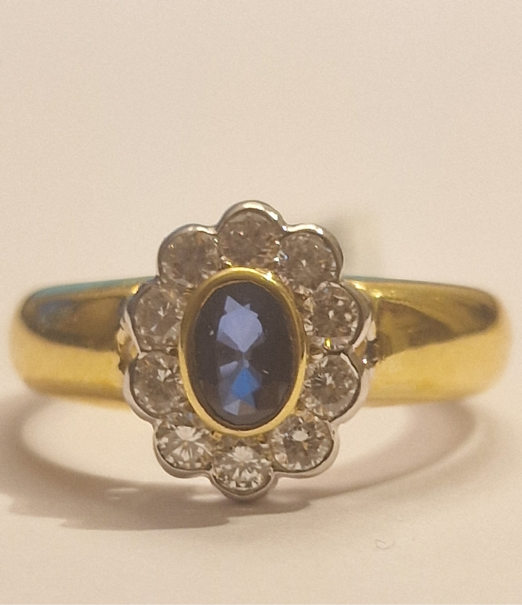 18k geelgouden ring met diamant gezet in witgoud met een ovale saffier als middensteen