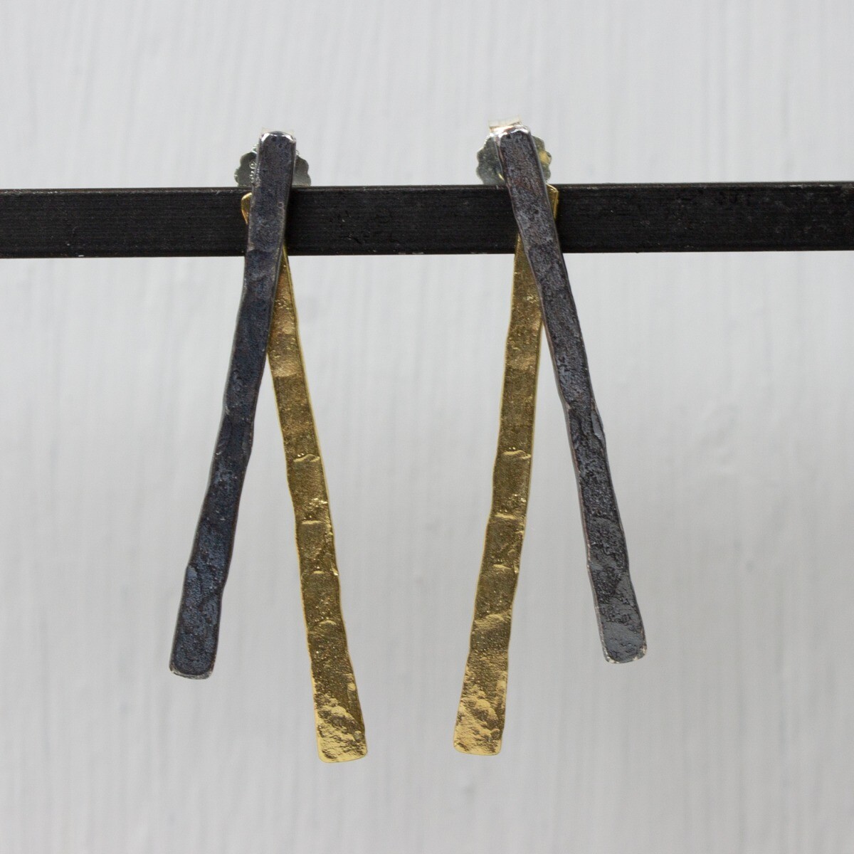 Oorsteker gemaakt van geoxideerd zilver en zilver verguld in de vorm van twee hamerslag staafjes. De glans van 925 sterling zilver maakt het een gewild edelmetaal voor de vervaardiging van sieraden. Het bestaat uit 92,5% puur zilver en 7,5% koper. Puur zilver is een zacht en buigzaam materiaal, het koper in 925 sterling zilver zorgt voor de stevigheid. De sieraden van Jeh Jewels zijn nikkel vrij. Op dit sieraad is gebruik gemaakt van geoxideerd zilver, dit is een oppervlakte bewerking. Het is mogelijk dat de geoxideerde laag na verloop van tijd door slijtage gaat vervagen. Vergulden is het bedekken van een voorwerp met een laagje goud. Dit artikel is door een goudbad gehaald wat ervoor zorgt dat het zilver volledig bedekt wordt met een laagje goud. Resultaat een mooie glanzende afwerking met een laagje echt goud wat ook wel silverplated of goldplated wordt genoemd.