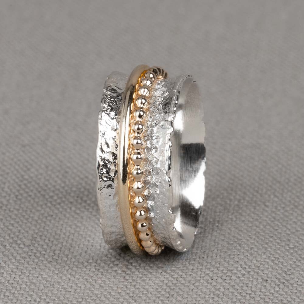 Bijzondere ring gemaakt van 925 sterling zilver en gold filled. De ringen in het midden van de ring kunnen bewegen, dit zorgt voor een speels effect. Let op: deze ring valt groot, omdat de ring rond loopt. Bij twijfel kies een maat kleiner. De glans van 925 sterling zilver maakt het een gewild edelmetaal voor de vervaardiging van sieraden. Het bestaat uit 92,5% puur zilver en 7,5% koper. Puur zilver is een zacht en buigzaam materiaal, het koper in 925 sterling zilver zorgt voor de stevigheid. De sieraden van Jeh Jewels zijn nikkel vrij. Gold filled komt uit Amerika en wordt daar al langer gebruikt voor de vervaardiging van sieraden met een "touch of gold" voor een betaalbare prijs. Het gold filled blijft op kleur, is slijtvast en de 14karaats goudlaag is dik genoeg om lang te kunnen genieten van de warme uitstraling van goud. Gold filled wordt veelal ook goed verdragen door mensen die allergisch zijn voor andere metalen dan goud.