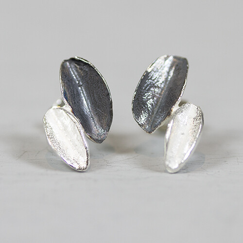 Oorbel gemaakt van 925 sterling zilver en geoxideerd zilver in de vorm van twee bladeren.
