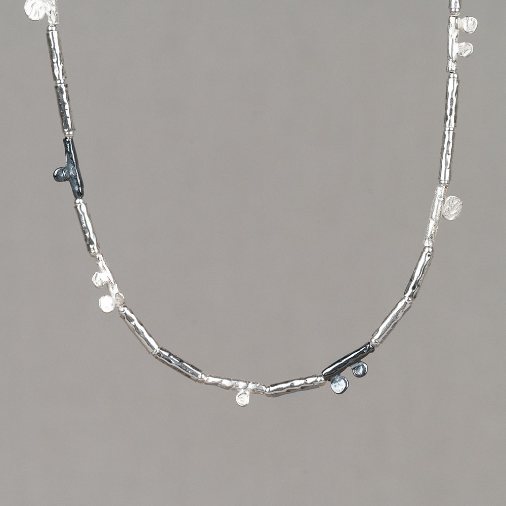 Collier gemaakt van 925 sterling zilveren en geoxideerde buisjes. Aan sommige buisjes zitten ronde deeltjes van hetzelfde materiaal. Combineer met een paar mooie oorbellen, een ring en armband voor een complete look!