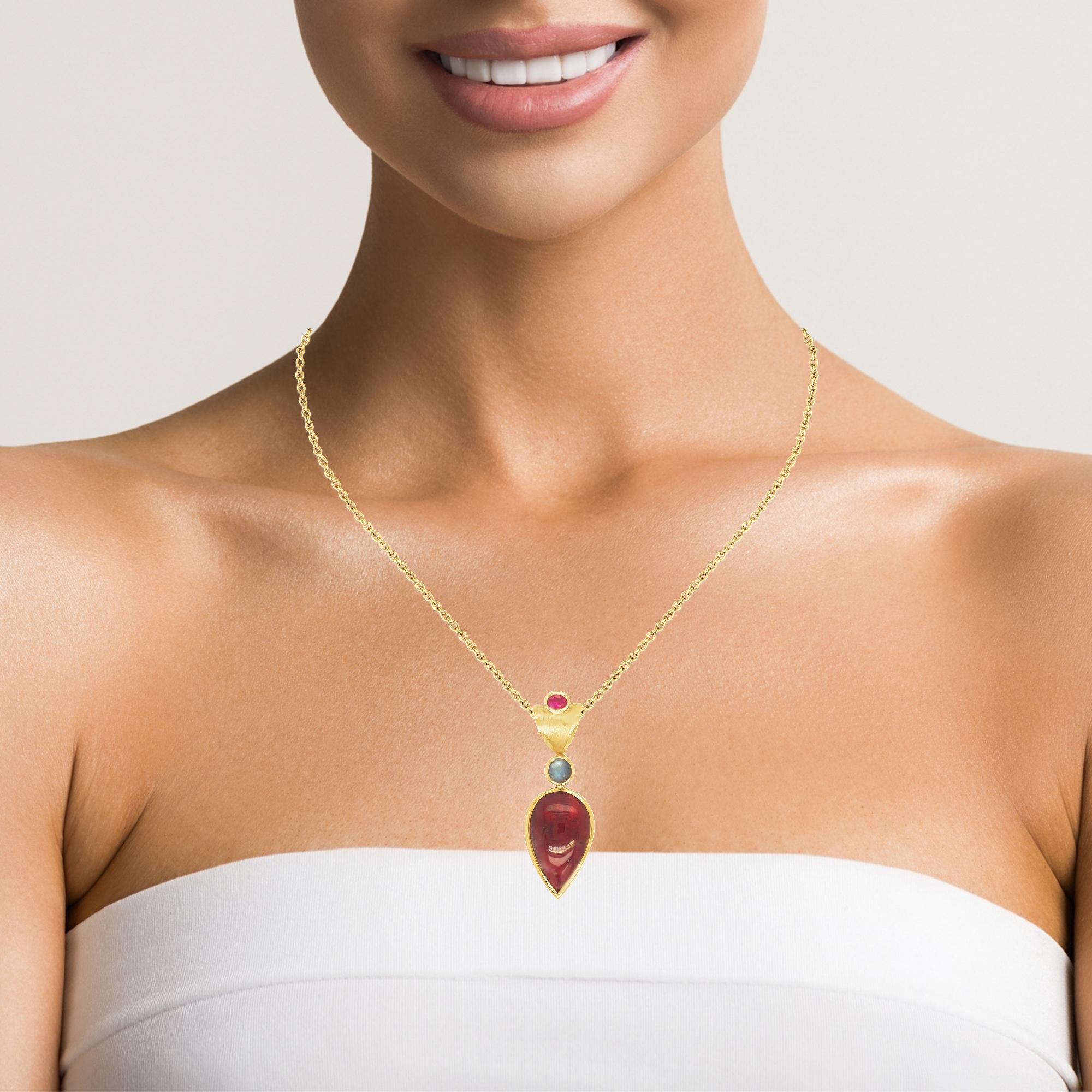 Dieser exquisite Schmuck aus edlem Gold in 750er besticht durch seinen eleganten Tropfenturmalin. Darüber angeordnet strahlt ein facettierter Mondstein, ein Rubin krönt das Ensemble. Perfekt als eleganter Blickfang an einer feinen Halskette, ideal für besondere Anlässe oder als stilvolles Alltagsaccessoire. Ein Must-Have für Schmuckliebhaber, die Eleganz und Exklusivität schätzen.