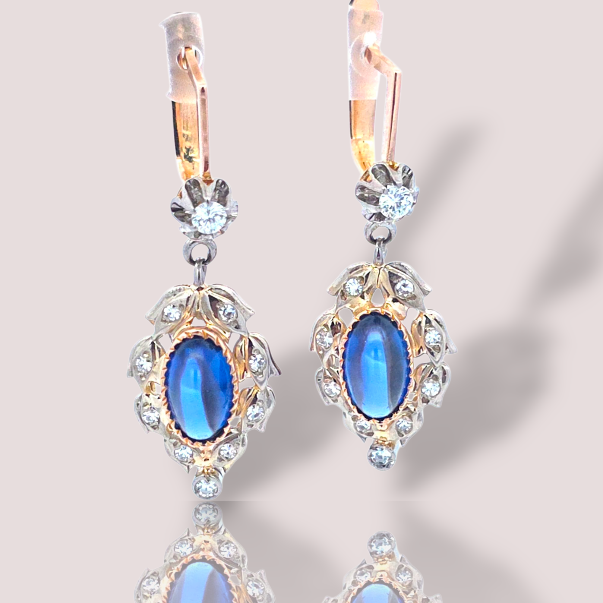 Deze prachtige vintage 14k rosé gouden oorbellen stralen elegantie uit met diamanten en cabochon geslepen synthetische saffieren. Deze oorbellen met gekleurde stenen voegen een verfijnde touch toe aan elke outfit. Draag ze bij speciale gelegenheden of om een alledaagse look te verfraaien. Ze zijn perfect als subtiel maar opvallend accent aan je sieradencollectie.

De oorbellen zijn 4 cm lang en bevatten in totaal circa 0,38ct aan diamanten.