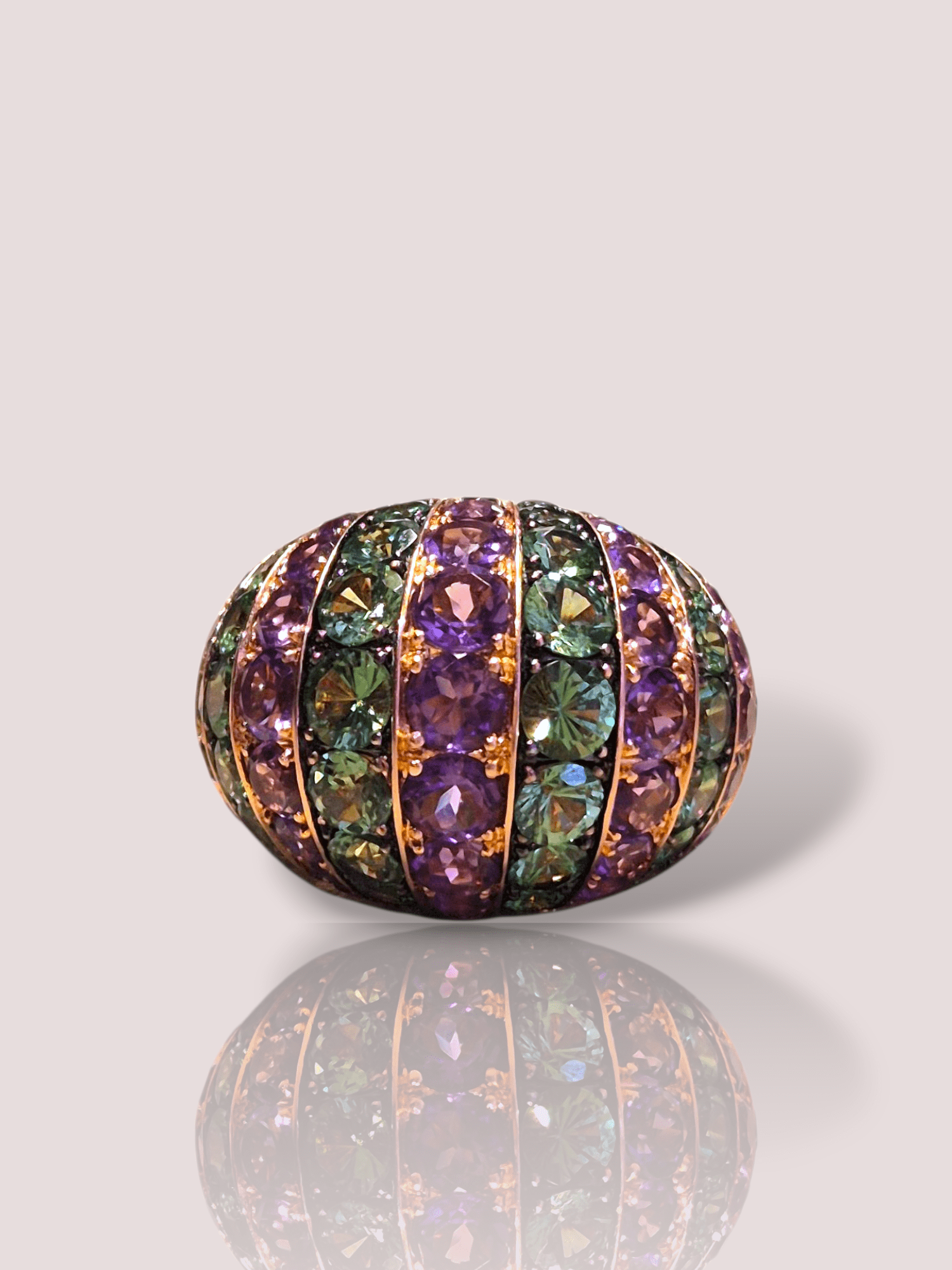Deze vintage 18k rosé gouden bombéring combineert een luxueus ontwerp met schitterende tsavoriet en amethist edelstenen. Deze unieke juweelring, gecategoriseerd als sieraad, straalt elegantie en stijl uit. Draag deze opvallende ring bij speciale gelegenheden of feestelijke avonden voor een verfijnde look. Perfect te combineren met andere roségouden sieraden voor een samenhangende uitstraling.

De ring bevat 54 prachtige groene tsavorieten en 54 prachtige paarse amethisten.
