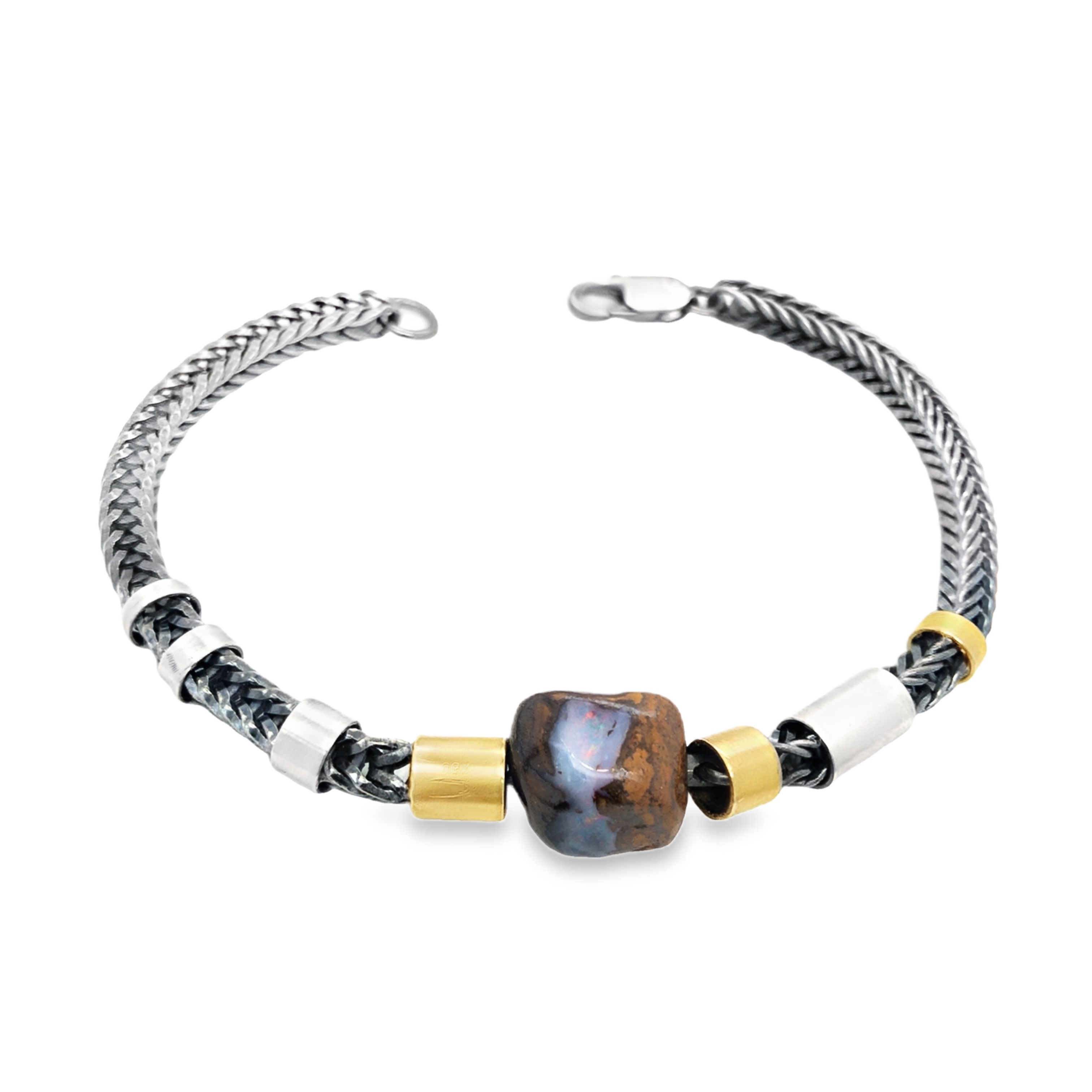 Entdecken Sie dieses einzigartige Armband, gefertigt aus edlem Silber und Gold 750. Das Schmuckstück wird durch einen faszinierenden Opal im Cabochonschliff veredelt, hier hat der Schleifer die dicke Opalschicht gekonnt zu einem dreidimensionalen Schmuckstein herausgearbeitet. Der aus Boulder/ Australien stammende Stein bietet ein vielseitiges Farbenspiel, das den Blick spätestens auf den zweiten Blick fesselt. Ein außergewöhnliches Accessoire, das Ihrem Stil eine individuelle Note verleiht. Perfekt für Liebhaber besonderer Schmuckstücke.