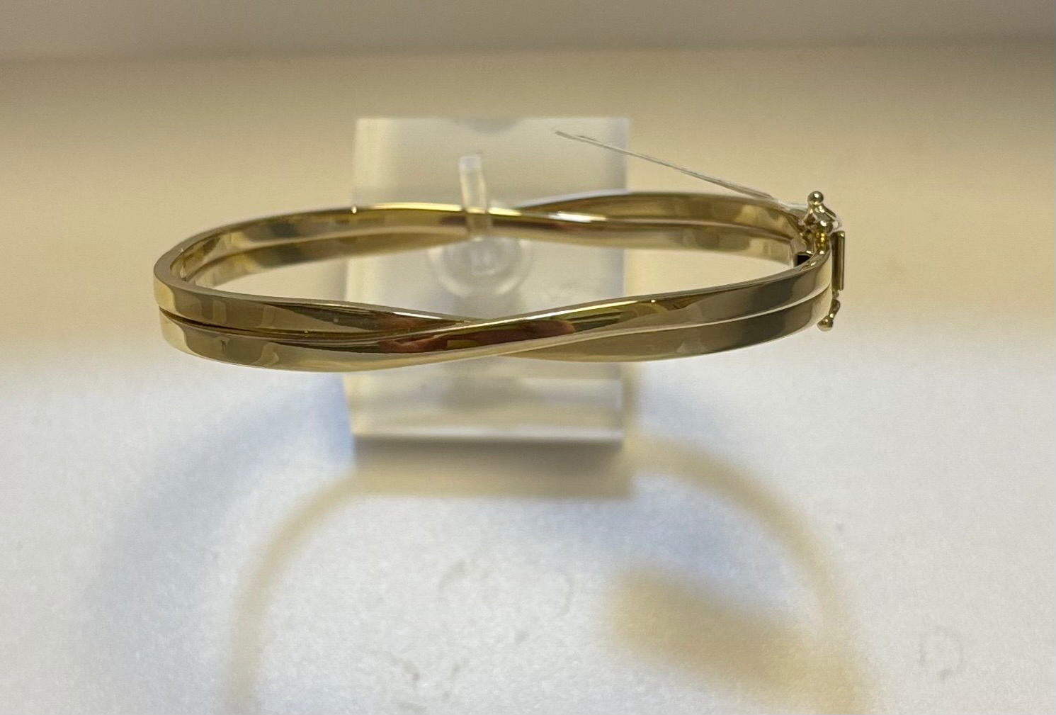 Goud bangle armband met scharnier en 2x vh8. 2 banen welke elkaar kruisen aan de bovenkant. Doorsnede; 61 mm, van 3 tot 6 mm breed. 